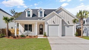 A two-story house with a front porch, a garage, and a well-maintained lawn. - Executive  style home with 4 bedrooms and 3.5 baths. (Saint Simons Island)