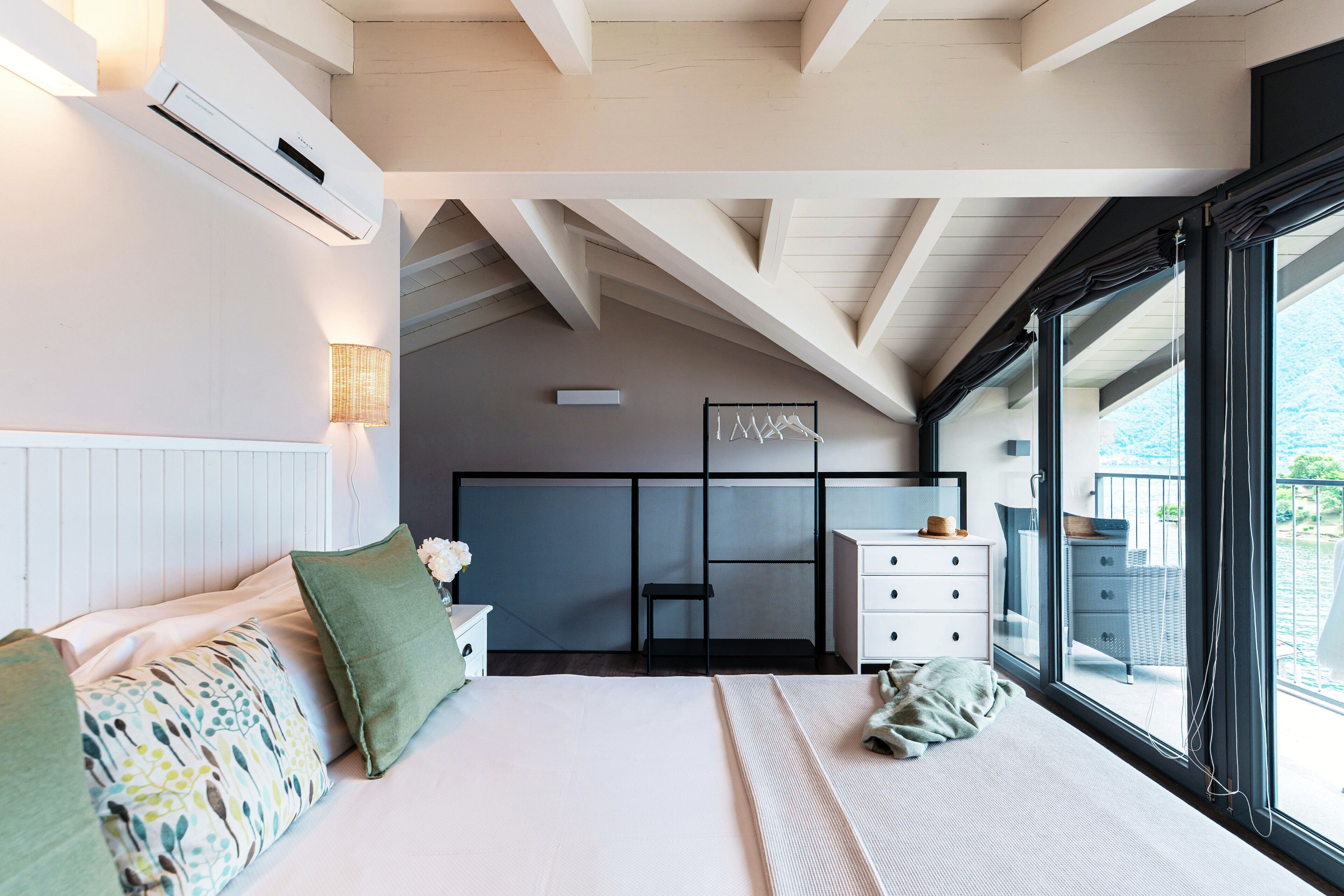 A bedroom with a large bed, a dresser, a mirror, and a window with a view.