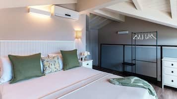 Ein Schlafzimmer mit einem Bett, Nachttischen, einer Lampe, einer Wand-Klimaanlage und einem Kleiderständer.