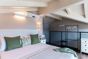 A bedroom with a bed, bedside tables, a nightstand, a lamp, a wall-mounted air conditioner, and a clothing rack. - Lake's Dream (Tremezzina)
