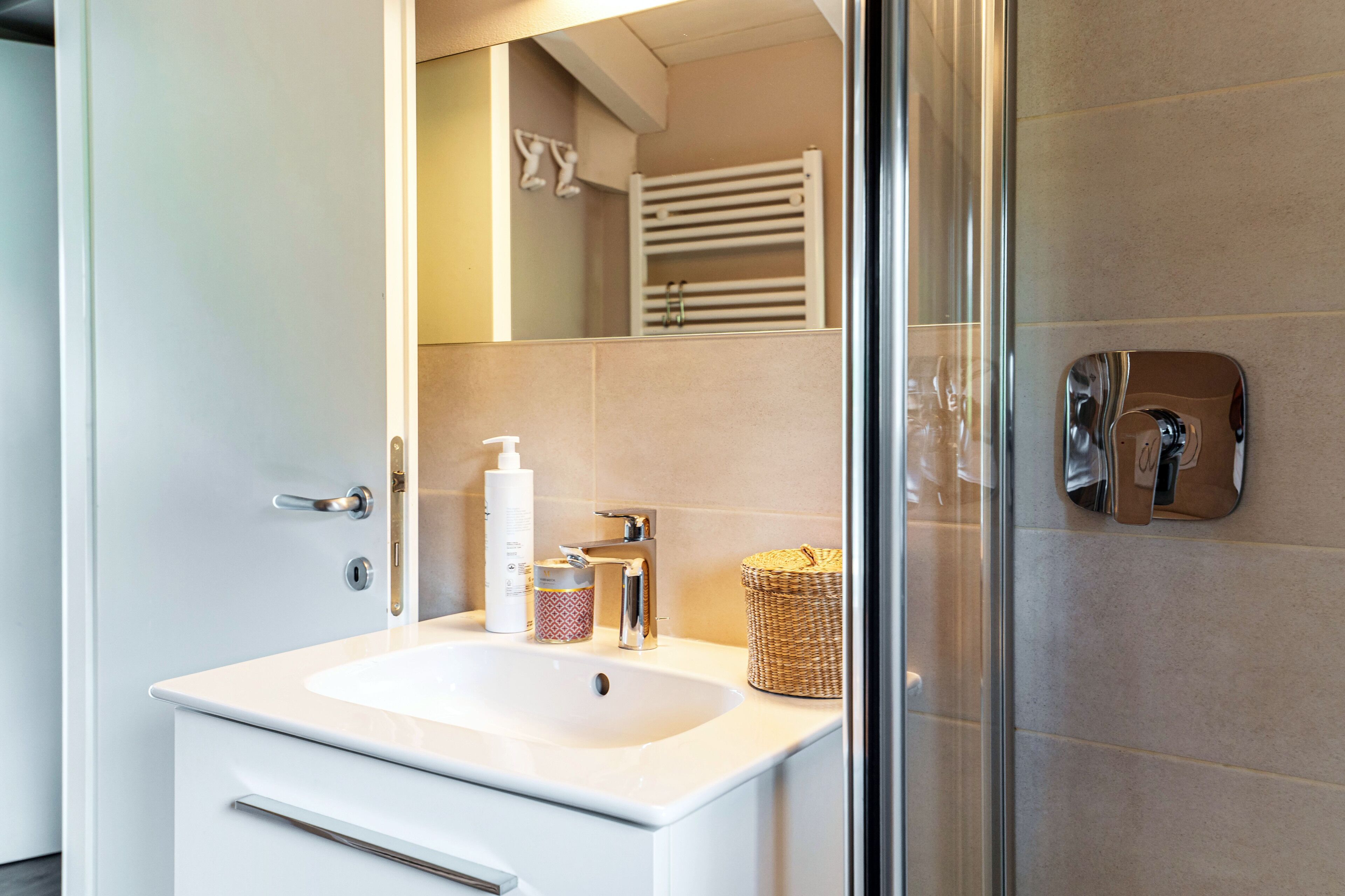 A bathroom with a white sink, a mirror, a towel rack, and a shower area.
