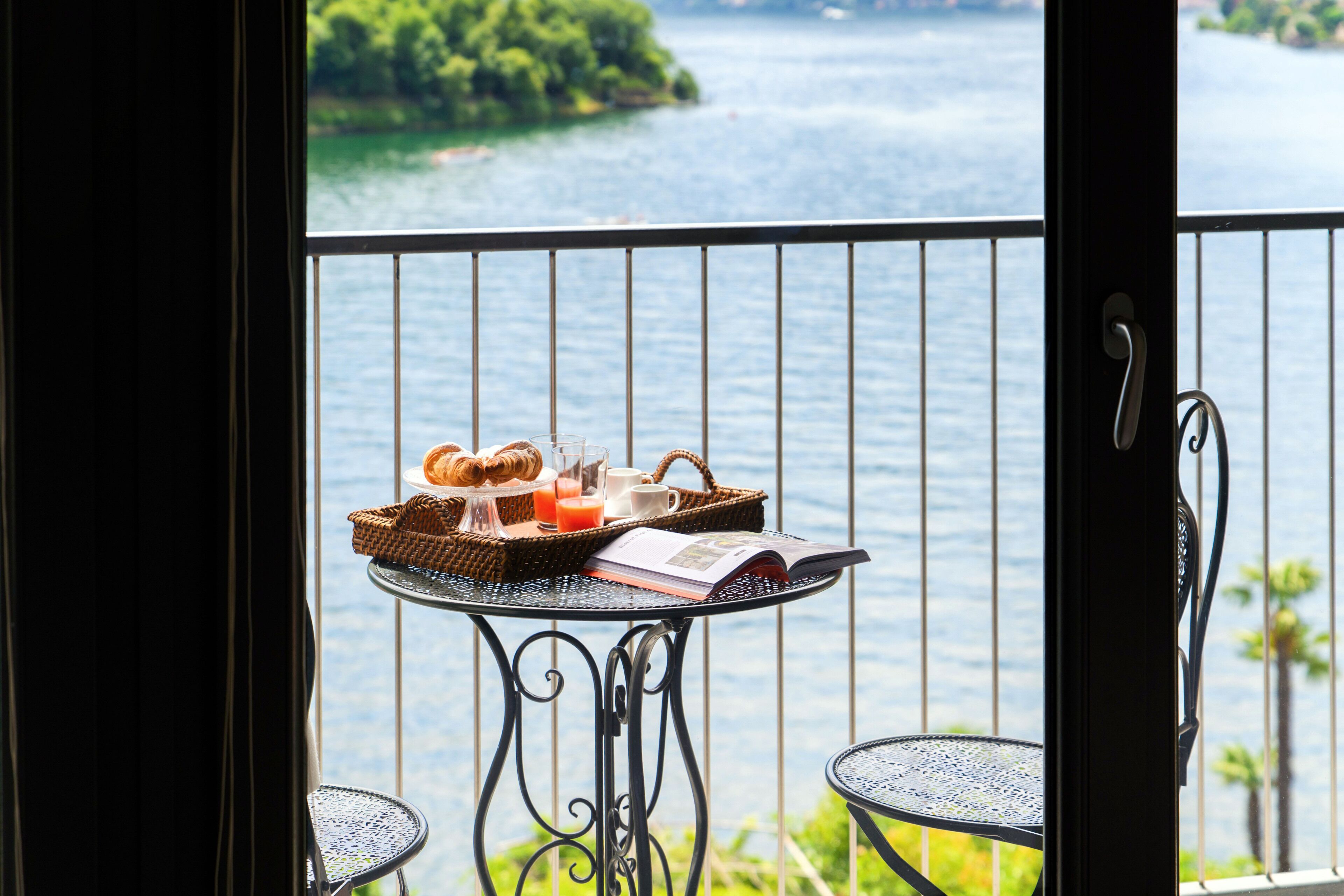 A balcony with a table set for breakfast, overlooking a body of water.