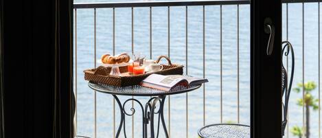 A balcony with a table set for breakfast, overlooking a body of water.