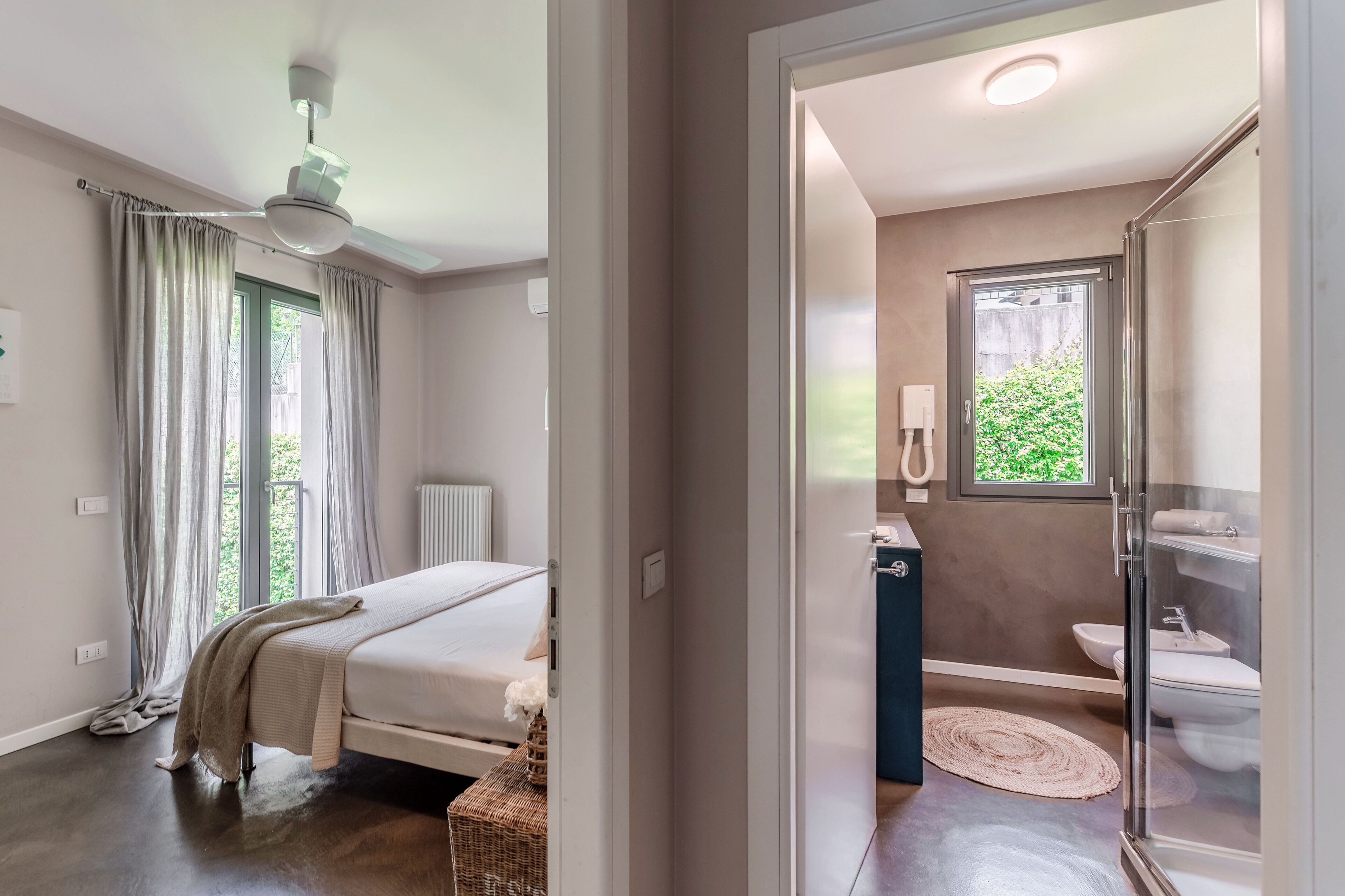 A bedroom with a bed, a window with curtains, a radiator, and a ceiling fan.