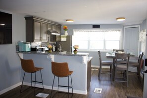 Une cuisine moderne avec un coin bar, deux tabourets de bar et une table à manger avec des chaises.