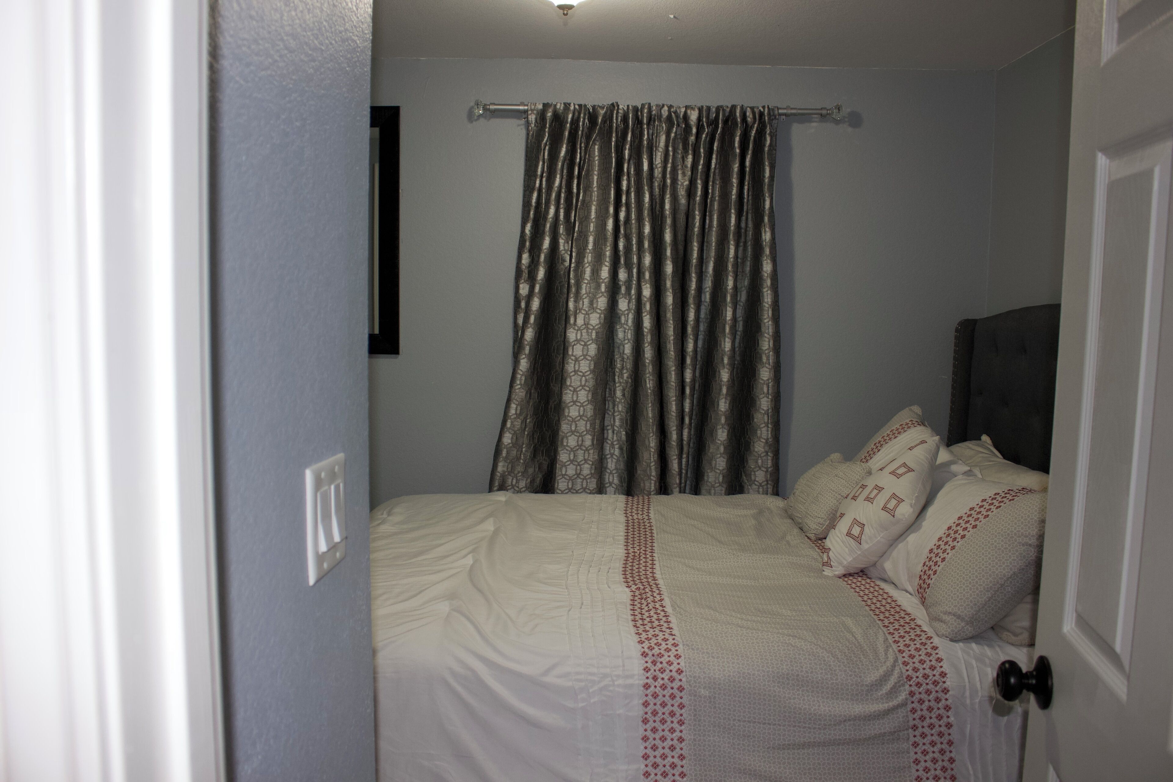 Une chambre à coucher avec un lit, des rideaux et une porte.