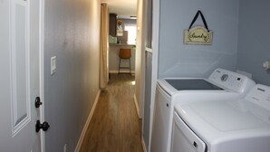 A laundry area with a washing machine and dryer, a chair, and a sign that says "Laundry".