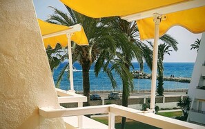 A balcony with yellow umbrellas, palm trees, and a view of the sea. - NEW Firstline Beach, Sea View, Aircon, fast WiFi, Pool, 2 Sunny Terraces Parking (Caleta de Vélez)
