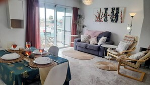 A dining area with a table set for four, a sofa, and a lounge chair.