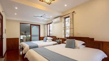 A hotel room with two beds, a wooden headboard, a ceiling light fixture, and a window with a view.