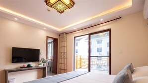A hotel room with a bed, a TV, a desk, and a balcony with a view. - Zhouzhuang Hefeng Xiyu Inn (Kunshan)