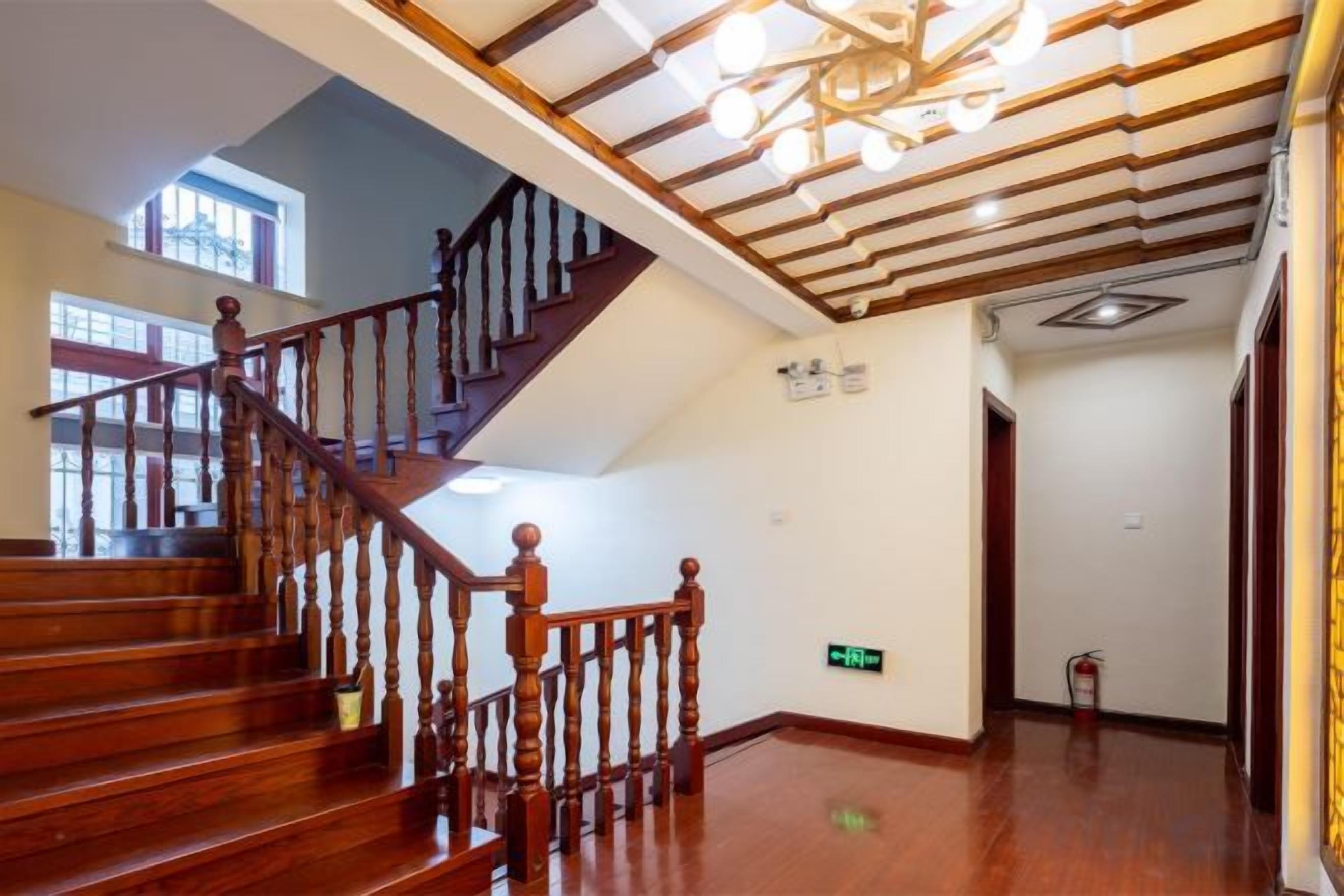 A wooden staircase with a handrail, a ceiling with exposed beams, and a fire extinguisher on the floor.