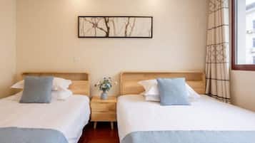 Une chambre d’hôtel avec deux lits, une table de chevet, un vase avec des fleurs et un tableau encadré au mur.