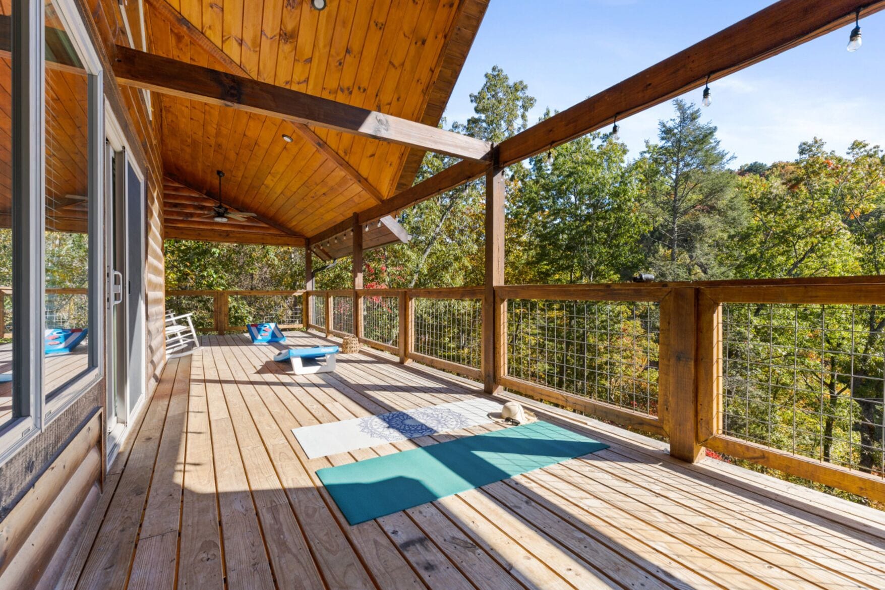 A wooden deck with outdoor seating and a view of trees.
