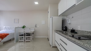 Una cucina moderna con mobili bianchi, un piano di lavoro in granito e un frigorifero integrato.