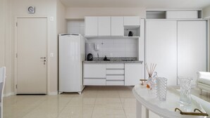 Una cucina moderna con mobili bianchi, un frigorifero e un tavolo da pranzo con bicchieri.