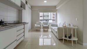 Una cucina moderna con mobili bianchi, un piano di lavoro in granito e un'area pranzo con un divano bianco e un piccolo tavolo.