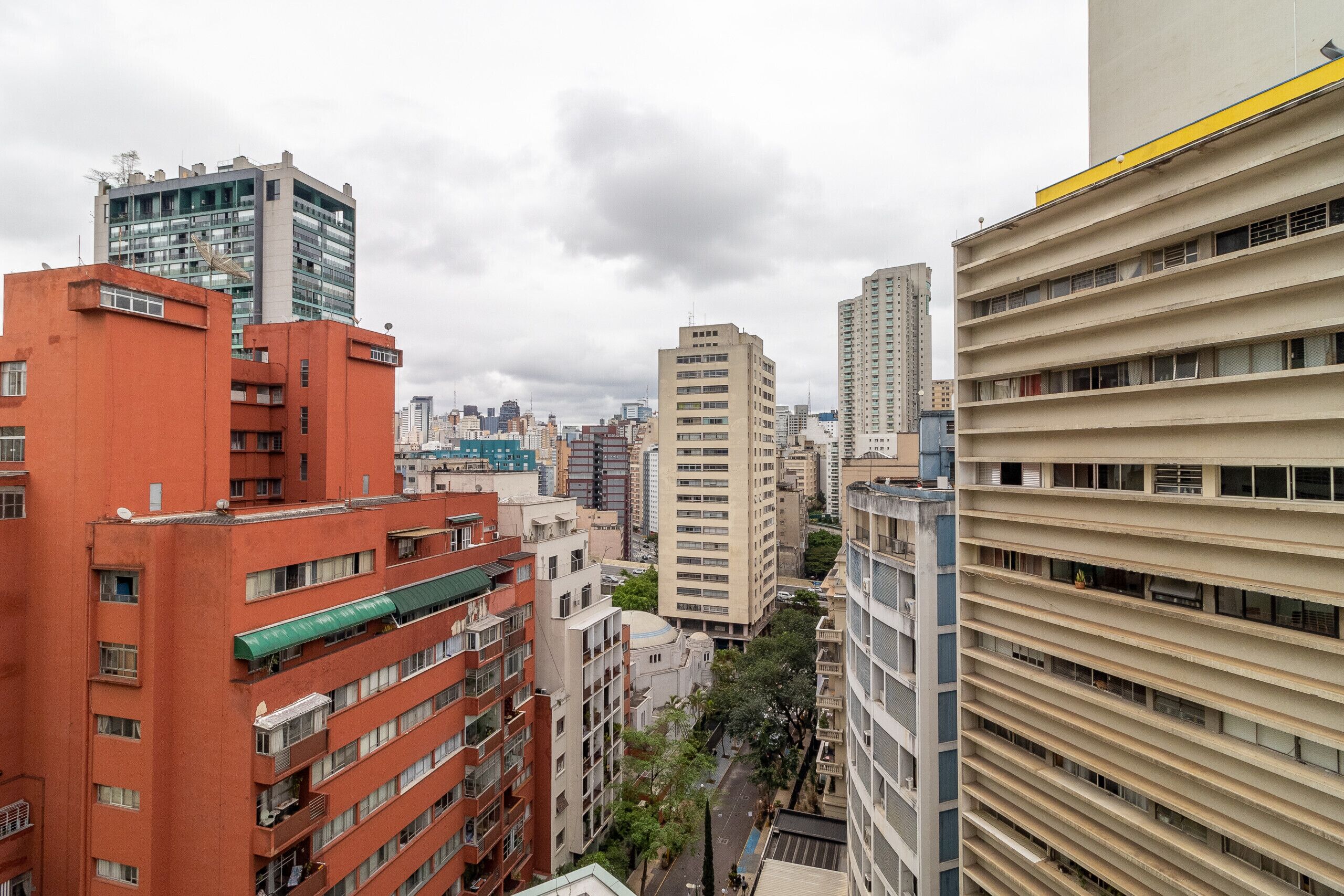 A high-rise building with multiple floors and balconies, surrounded by other tall buildings.