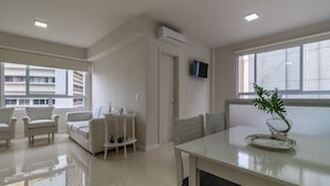 Un soggiorno moderno con un divano, poltrone, un tavolino con oggetti decorativi e un'ampia finestra vista edifici.