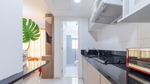 A modern kitchen with a black countertop, wooden cabinets, and a large green plant. - AV0905 - Studio Avanhandava (São Paulo)