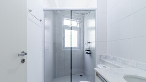 A modern bathroom with a glass-enclosed shower, a toilet, and a sink with a marble countertop. - AV0905 - Studio Avanhandava (São Paulo)