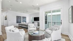 A modern living room with white furniture, a round coffee table, and a large window with a view.