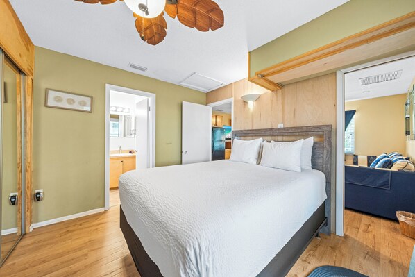 Un dormitorio con una cama grande, techo de madera y vistas a la cocina.