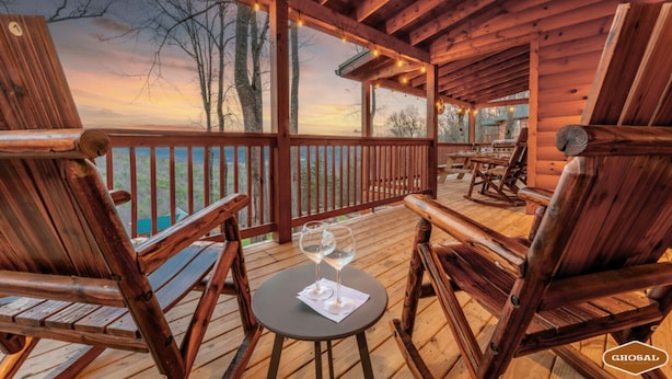 Een houten terras met schommelstoelen en een tafel, met uitzicht op een prachtig landschap.
