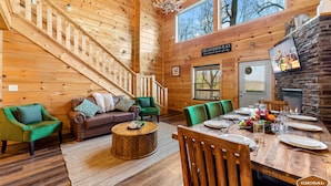 Een gezellig cabin interieur met een houten trap, een eethoek voor vier personen en een open haard.