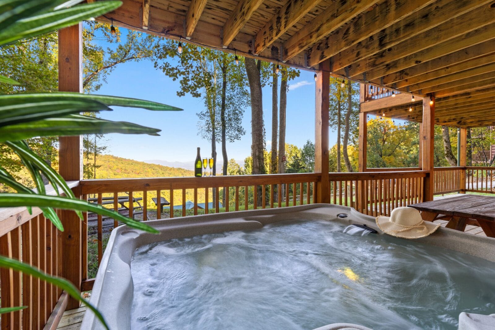 A hot tub with a wooden deck and a view of trees and hills.