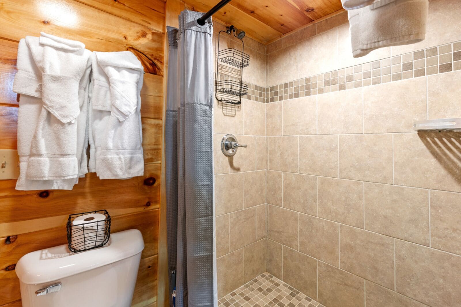 Un interno in legno con una doccia, pareti piastrellate e un WC.