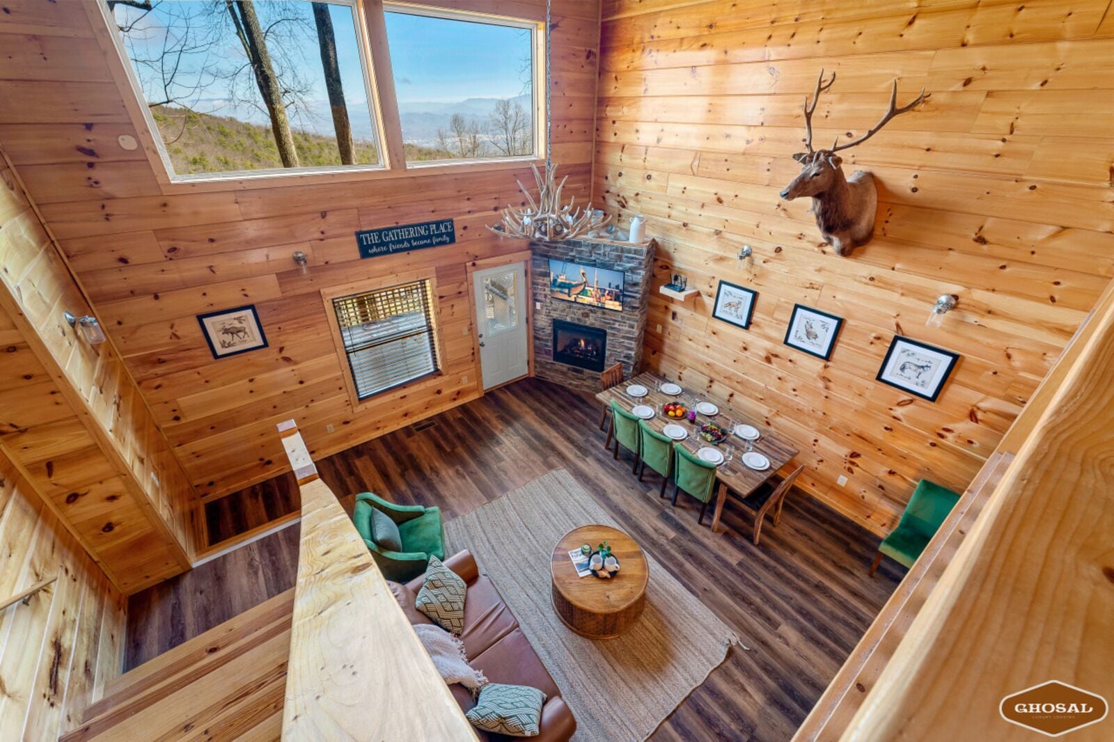 L’intérieur chaleureux d’un chalet avec un coin repas, une cheminée et une tête de cerf accrochée au mur.