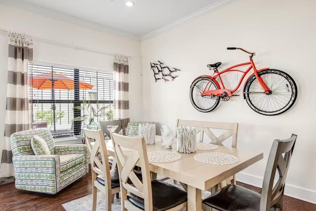 A dining area with a wooden table, four chairs, and a red bicycle mounted on the wall.