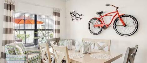 A dining area with a wooden table, four chairs, and a red bicycle mounted on the wall.
