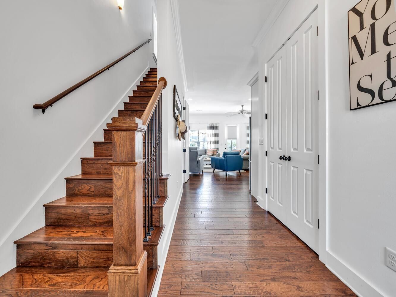 Un escalier en bois mène à un espace de vie agrémenté d’un canapé bleu et de murs blancs.