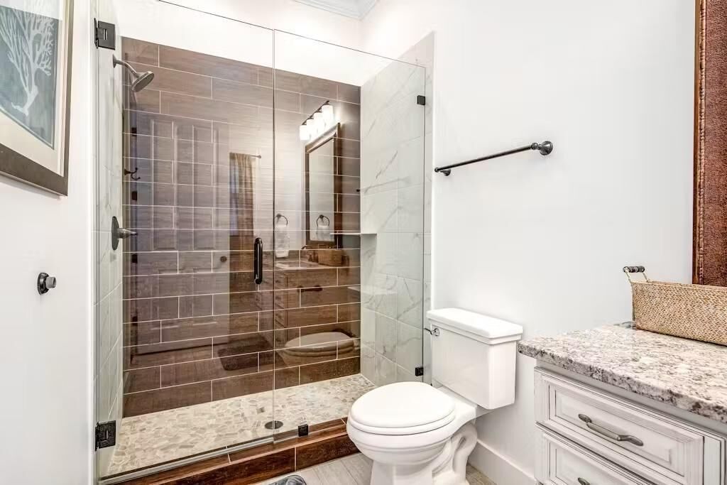 A modern bathroom with a glass-enclosed shower, a white toilet, and a marble countertop.