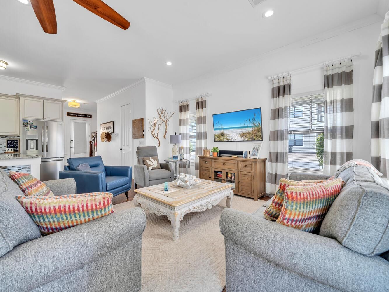 A spacious living room with grey sofas, a wooden coffee table, and a television.