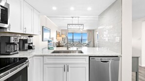 A modern kitchen with white cabinetry, a stainless steel sink, and a dishwasher. - Emerald Towers 305 (Destin)