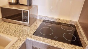Een keuken met een magnetron, waterkoker en een fornuis.