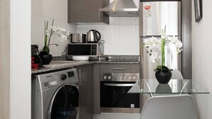 Een moderne keuken met roestvrijstalen apparatuur, een glazen tafel en een potorkidee.