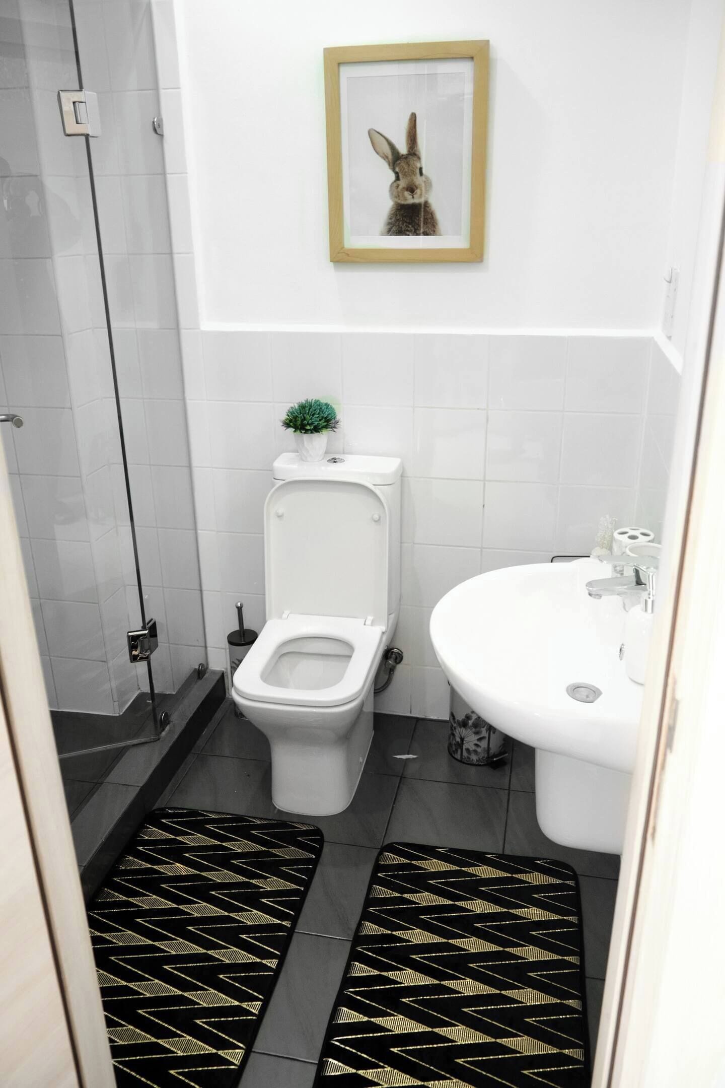 A bathroom with a toilet, sink, and a framed picture on the wall.
