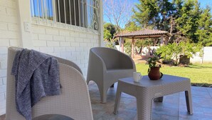 Un patio con due poltrone in vimini, un tavolino e una pianta in vaso.