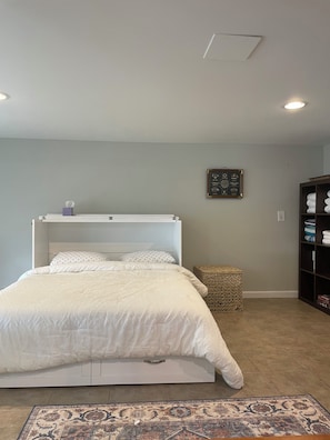 Cozy retreat with a single bed, white linens, and a woven stool.
