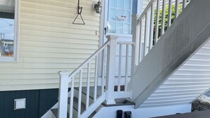 A covered outdoor area with a staircase leading to a door with a 'Welcome' sign. - Beachfront Bliss: Water Front, Steps to Sand, Minutes from Dining & Attractions! (New London)