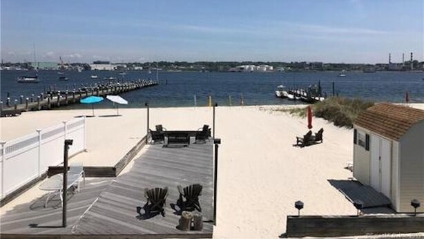 A beach view with a wooden deck, lounge chairs, and a small building. - Beachfront Bliss: Water Front, Steps to Sand, Minutes from Dining & Attractions! (New London)