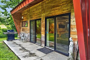A wooden exterior with sliding glass doors, a barbecue grill, and outdoor seating.