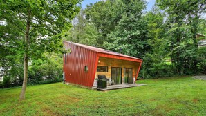 A small, red wooden cabin with a covered porch, surrounded by lush greenery. - Nordic Eco House - Black Mountain (Black Mountain)