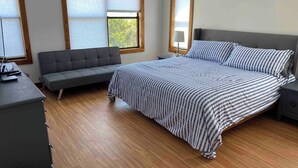 Ein Schlafzimmer mit Bett, Sofa, Kommode und Nachttisch.