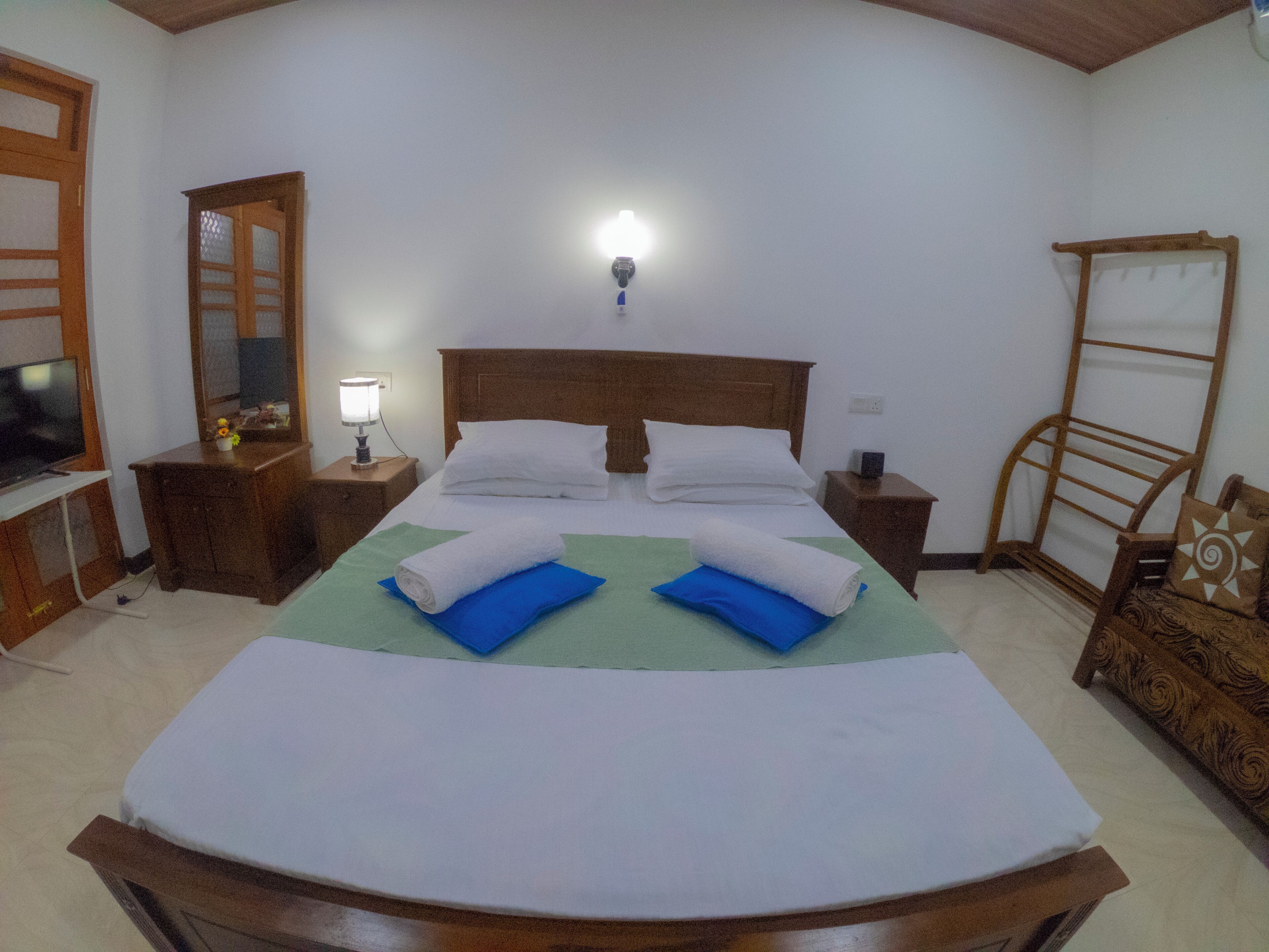A neatly arranged bedroom with a large bed, two bedside tables, a nightstand, a wooden chair, and a mirror.