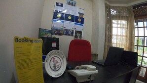 A reception desk with a computer, a telephone, and a sign for Booking.com. - Innovick Residence (Kandy)